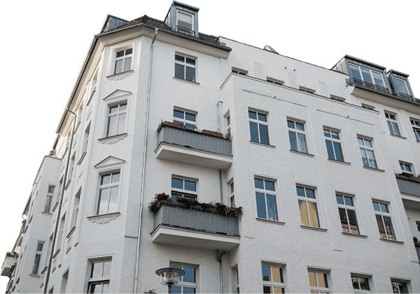 Weißes Mehrfamilienhaus mit Balkonen und großen Fenstern in einer urbanen Umgebung.